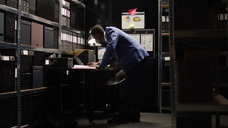 Male inspector collecting clues, analyzing statements, and utilising laptop to uncover facts in an...