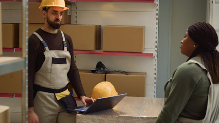 Tracking shot of worker and colleague inputing updated products info on online shopping website,...