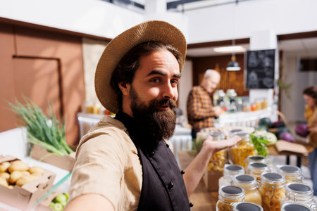 Zero waste shop entrepreneur using selfie camera on mobile phone to promote environmentally responsible vegan products online. Bio supermarket owner making marketing contentの写真素材