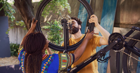 Active sporty interracial couple safely securing front bicycle tire after repair ready for summer...