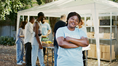 African American female volunteer grins and poses during a food drive charitable event. Humanitarian aid program that provides hunger relief and help to the homeless and the poor. Portrait shot.の写真素材