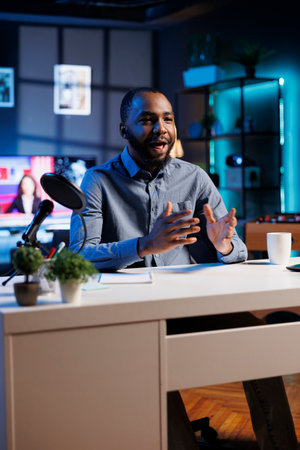 African american content creator using professional recording equipment to film vlog channel intro for online streaming platforms. Media star greets fanbase, presenting today video topicの写真素材