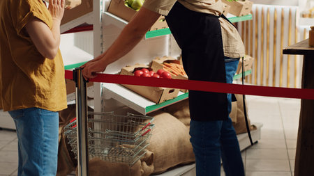 Vendor greeting first clients in newly opened zero waste supermarket, removing red ribbon. Storekeeper welcoming shoppers inside environmentally responsible local neighborhood storeの写真素材