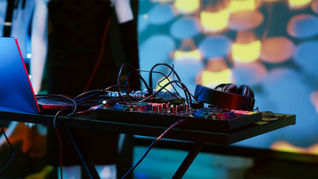 Empty DJ mixing panel at funky club, spotlights and disco ball at the bar used for dancing and...