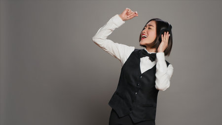 Front desk staff dancing around in studio and listening to music, having fun with modern songs on audio headset. Administrator enjoying fun tunes and showing dance moves. Camera A.の写真素材
