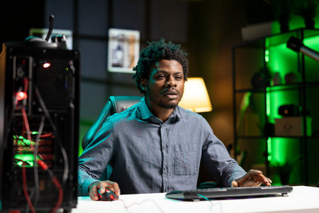 Man plays difficult singeplayer videogame, spamming attack buttons to defeat enemies. African american gamer in living room focused on winning game, pressing hard on keyboard keysの写真素材