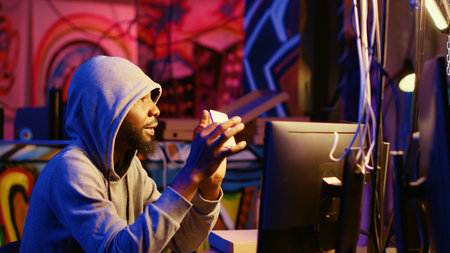 Hacker holding SSD device with valuable information after doing data breaches and financial theft. Cybercriminal with gathered users bank account credentials ready to sell it on black marketの写真素材