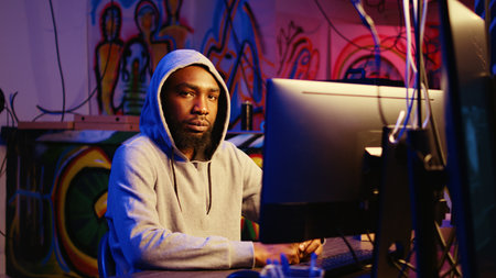 Close up shot of african american man hacking systems, stealing credit card numbers and manipulating banking systems for his own personal gain. Zoom in on evil hacker running code in basementの写真素材
