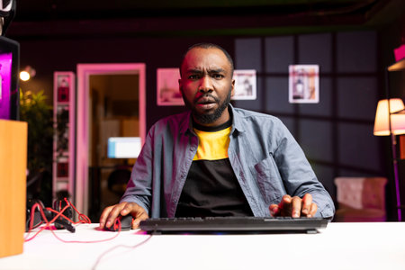 Upset gamer frustrated after losing online competitive multiplayer match playing on cutting edge gaming setup. Man feeling sad after being defeated in videogame on computerの写真素材