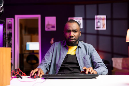 Upset african american gamer frustrated after losing online competitive multiplayer match playing on cutting edge gaming setup. BIPOC person feeling sad after being defeated in internet videogameの写真素材