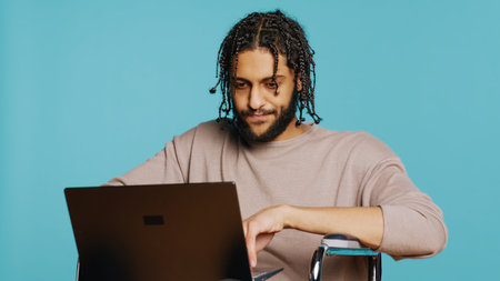 Middle Eastern man composing email, typing on laptop keyboard, struggling to think of what to write....