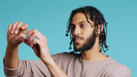 Happy person using augmented reality technology, doing swiping motions. BIPOC man using futuristic AR tech, making pinching zooming gesturing, blue studio background, camera B close upの写真素材