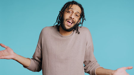 Uncaring Middle Eastern man shrugging shoulders, showing indifference and apathy. Careless BIPOC person doing nonchalant indifferent hand gesturing, isolated over studio background, camera Bの写真素材