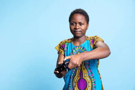 African american woman enjoying gaming challenge in studio, playing videogames with a controller. Smiling young adult having fun with online gaming championship, participates in cyber sport.の写真素材
