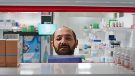 POV of pharmacist placing medicaments boxes on shelves, organizing types of medicine in pharmacy. Medical assistant putting supplements or treatments on prescription, insurance services. Tripod shot.の写真素材