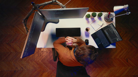 Aerial shot of computer scientist listening music while writing lines of code during remote job...
