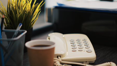 Cup of coffee on office desk next to paperwork containing business financial information income statements, close up shot. Company invoice documents and hot beverage in accounting workspaceの写真素材