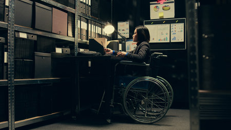 Wheelchair user conducting private investigation in disability friendly incident room, examining old cases to find connections. Detectives gathering legal information for identification. Camera B.の写真素材