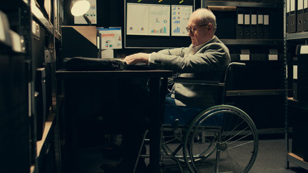 Paralyzed senior inspector reviewing classified case records in incident room, gathering intelligence for private investigation. Wheelchair user with limited mobility accessing databases. Camera B.の写真素材