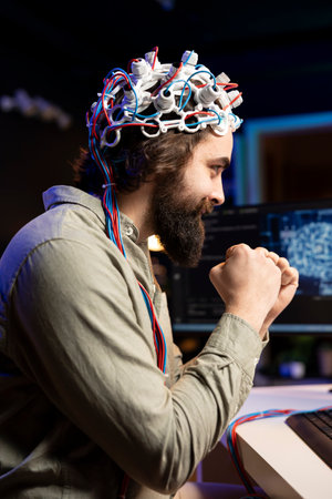 Smiling man with EEG headset on happy after transferring mind into virtual world, becoming one with AI. Cheerful transhumanist celebrating after gaining superintelligence using neuroscientific techの写真素材