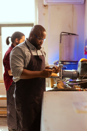 African american carpenter looking at screwdriver, preparing to start production in furniture assembly shop. BIPOC cabinetmaker at workbench inspecting tool, ready to work on wood designsの写真素材