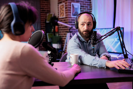 Show presenter interviewing designer during live stream, talking about fashion and style trends. Man having conversation with social media influencer, recording episode for podcastの写真素材