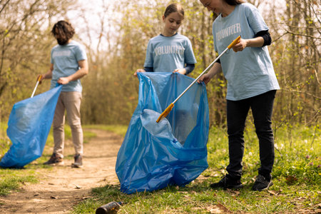 Diverse people collecting rubbish and storing in the trash disposal bag, picking up junk and plastic bottles to help with pollution. Clearing the forest, ecosystem protection.の写真素材