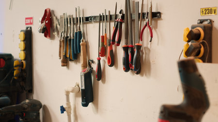 Close up of electric router with woodworking tools on rack in background in workshop. Focus on hand...