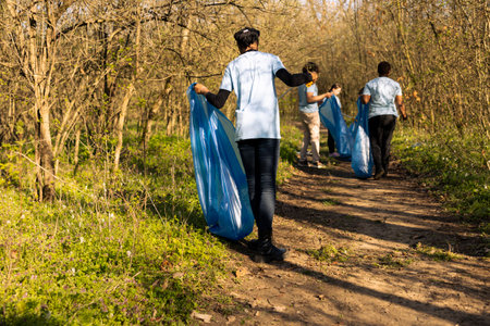 African american climate change volunteer grabbing trash in a bag, working to protect the natural environment. Volunteering for nature conservation and community service action.の写真素材