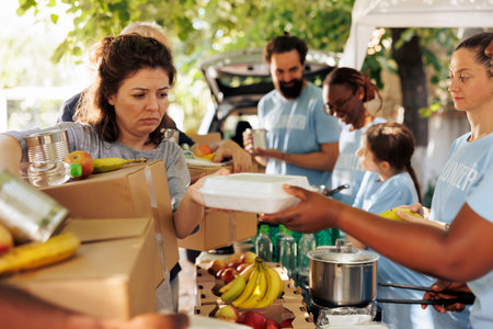 Multiracial group offers assistance by distributing food to the poor and needy. Volunteers of different ethnicities join together to aid homeless people by participating in humanitarian food drive.の写真素材