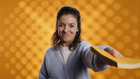 Portrait of upbeat content creator reviewing newly published books, presenting synopsis to audience. Media star sponsored by publisher to show new novel releases to subscribers, studio backgroundの写真素材