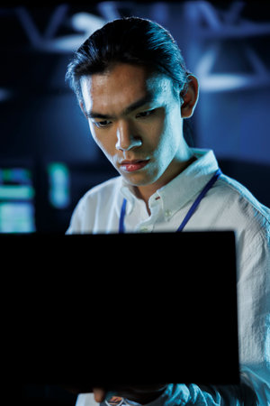 Dara center IT consultant running code and programming on laptop, troubleshooting and upgrading high tech facility designed to accommodate rows of fully operational server mainframesの写真素材