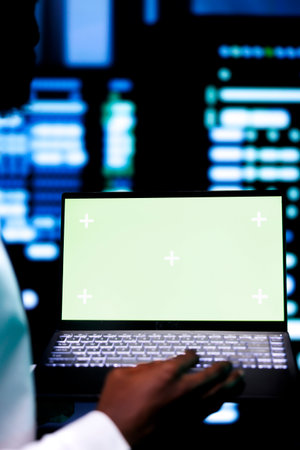 Close up shot of specialist examining server cabinets performance trends using chroma key device. Employee using mock up laptop to spot data center operational issues causing servers to malfunctionの写真素材
