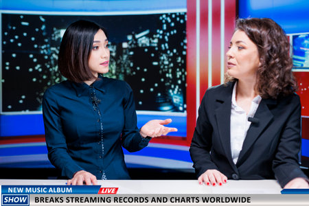Journalists team talk about new music album, women night show hosts reveal song breaking top charts and records at global scale. Newscasters discuss about streaming and selling success.の写真素材