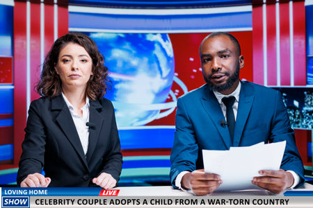 Reporters talking about famous couple adopting child from country at war, helping a kid to live normal life. Diverse journalists discuss about amazing gesture done by celebrities, morning show.の写真素材
