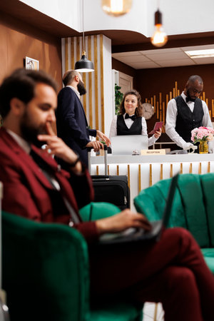 Passport id check in, businessman registering at hotel reception counter with professional employees. Entrepreneur talking to receptionist, reviewing identification documents.の写真素材
