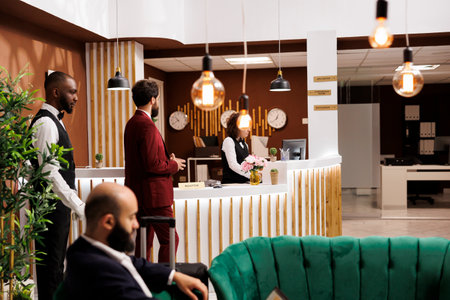 Hotel staff providing luxury services for businessman travelling to attend executive conference, reception lobby. Traveling for work, entrepreneur doing check in at front desk.の写真素材
