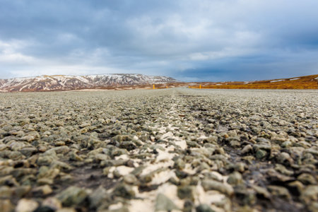 Icelandic landscape and long road in scandinavian scenery with empty roadside, frozen lands and fields in iceland. Spectacular panoramic view of arctic countryside, snowy mountains tops.の写真素材