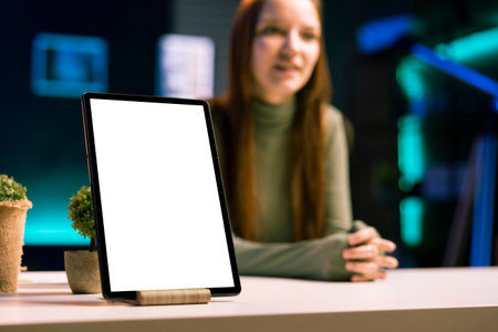 Focus on mockup tablet with gen Z teenager in blurry background doing review, comparing features. Close up shot of isolated screen portable device analyzed by influencer, filming online videoの写真素材