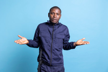 African american clueless security agent does i dont know sign in studio, raising his shoulders and acting confused or uncertain about something. Doubtful bodyguard is unsure on camera.の写真素材