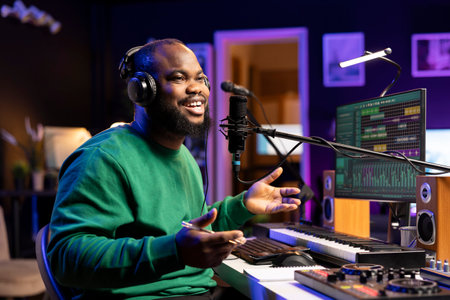 Happy pleased songwriter recording a new track in home studio, using audio gear and microphone to add acoustics and improve sound quality. Artist composing music for a debut album.の写真素材