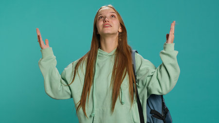 Pious woman looking up towards sky, waiting for sign from god. Spiritual girl doing worship hand gesturing, spreading arms, hoping for miracle, studio background, camera Aの写真素材