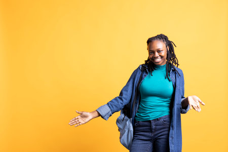 Happy young woman doing shrugging shoulders gesture, showing relaxed mood. Serene BIPOC girl doing...