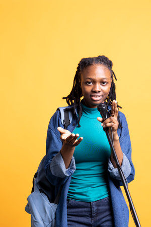 African american woman holding microphone, performing songs in concert, isolated over studio background. Energetic BIPOC musician singing to spectators, doing karaoke, having funの写真素材