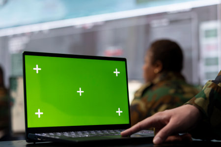 Trooper utilizing chroma key mockup screen on a laptop in military headquarters, providing real time data to ensure national safety. High ranking serviceman uses pc with copy space display.の写真素材