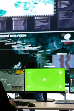 Military specialist monitoring warships traffic activity along the national coast, uses green screen to ensure safety. Professional IT operator working in power base command post.の写真素材