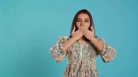 Woman covering eyes, ears and mouth, imitating three wise monkeys. Indian person doing don`t see, don`t hear and don`t speak hand gesturing concept, studio background, camera Aの写真素材