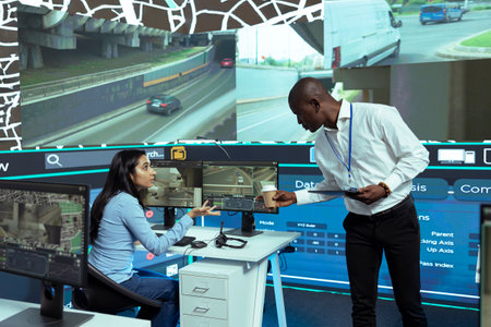 African american supervisor gives insight to indian operator in control center, shipping agency working on express delivery and logistics. Employees guiding couriers in the field.の写真素材