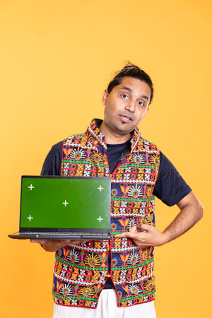 Portrait of tech professional pointing finger towards green screen laptop, isolated over studio backdrop. Content creator doing technology reviews, presenting mockup notebookの写真素材
