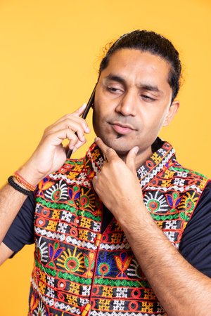 Man talks with friend over telephone call, doing stroking chin gesture. Pensive person talking with mate in phone call, thinking and processing information received, studio backgroundの写真素材